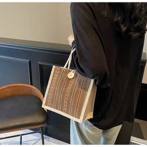 Close-up of linen tote bag with brown stripes, rope handles and decorative wood button