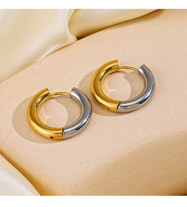 Close-up of chunky two-tone gold and silver steel hoop earrings with polished finish