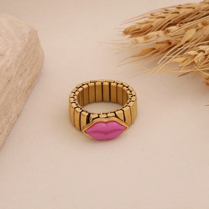 Detail view of pink lip-shaped ring with golden flexible metal band on natural stone