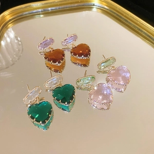 Close-up of heart-shaped crystal earrings in four colors on a gold mirror tray