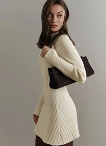 Detail of cream long-sleeved knitted A-line dress paired with a brown leather handbag