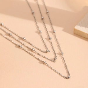 Close-up of triple-layered silver stainless steel bead chain necklace for women