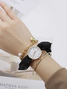 Luminous daisy watch with black fabric strap and gold bracelet set on model's wrist