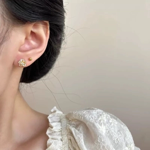 Elegant gold flower and ball stud earring set for women shown on model's ear