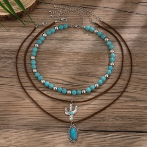 Macro shot of boho turquoise beaded necklace and cactus pendant on natural wood backdrop