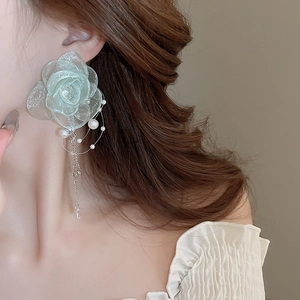 Close-up of light green silk flower earrings with pearls and elegant metal tassels