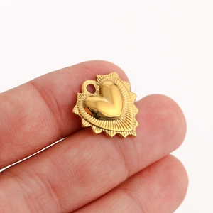 Macro shot of gold stainless steel heart pendant with textured sunburst design and ring