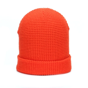 Macro shot of bright orange waffle knit beanie texture and cuffed winter hat edge