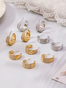 Detail of vintage C-shaped earrings with micro-pave zircons and floral patterns