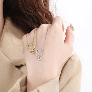 Detail of gold and silver kitten silhouette necklaces held by a model in casual attire