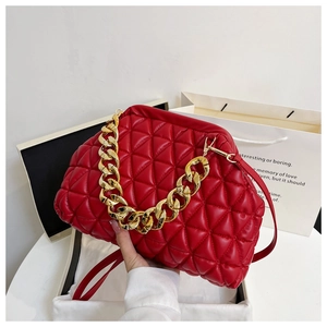 Detail of red quilted leather handbag with gold chain strap and textured diamond pattern