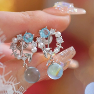 Detail of silver fishtail earring with blue zircon, iridescent sphere and pearl charm