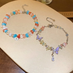 Detail of beaded bracelets with purple butterfly pendants and adjustable metal chains