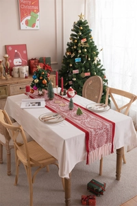Close-up of red knitted Christmas table runner featuring white patterns and fringe details