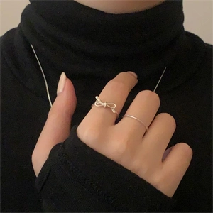 Detail of S925 sterling silver bow ring and minimalist band on model's hand