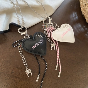Close-up of heart leather pendants with tooth charms on braided cord and ball chain