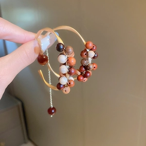 Detailed close-up of woven C-shaped earrings with colorful sandalwood beads and gold metal