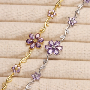 Macro shot of gold and silver bracelets featuring purple gemstone flowers and diamond leaves