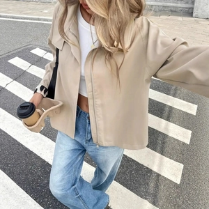 Street style shot of a beige utility zip-up jacket paired with vintage wash blue jeans