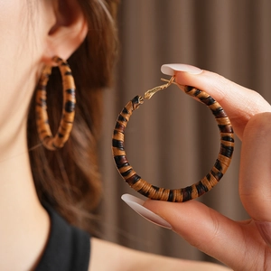 Détail de créoles élégantes avec motif léopard et texture en cuir tressé chic