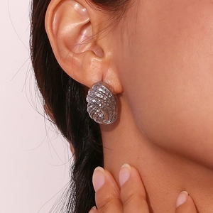 Macro detail of silver geometric earrings with irregular hammered and spiral texture