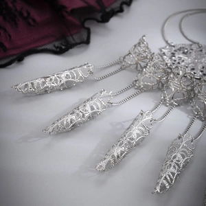 Detail of silver Gothic armor ring with hollow patterns and intricate metal chains