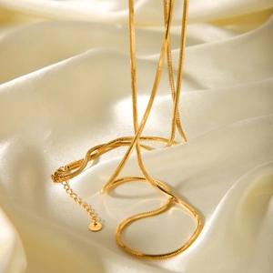 Detail of 18K gold stainless steel snake chain necklace on elegant white silk fabric