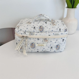Detail of blue striped quilted cosmetic bag with teddy bear pattern and bow handle