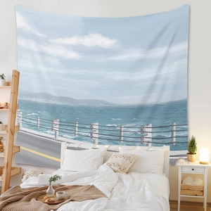 Coastal road scenery tapestry hanging over a bed in a minimalist white bedroom setup