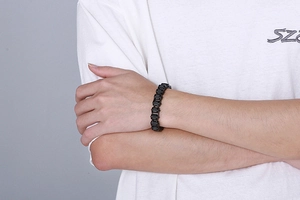 Close-up of a black stainless steel bicycle chain bracelet on a male model's wrist