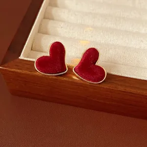 Elegant red velvet heart earrings with gold metal frame displayed on a jewelry box