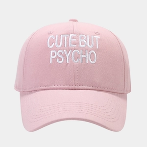 Close-up of pink cotton baseball cap with white Cute But Psycho embroidery text