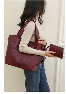 Detail of burgundy tote bag with matching pouch shown on a model for a chic urban look