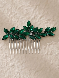Close-up of bridal hair comb with emerald green gems on a silver metal base