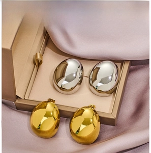 Macro shot of gold and silver teardrop earrings in a jewelry box with silk details