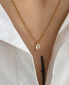 Close-up of gold chain necklace featuring a square-cut zircon pendant on white shirt