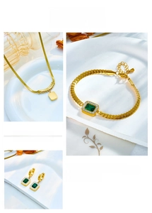 Macro detail of emerald green zircon necklace and bracelet set in gold finish