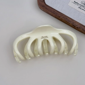 Détail d'une pince à cheveux pieuvre beige crème avec texte Barrette LaFrance et dents