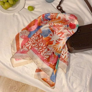 Colorful floral paisley silk scarf displayed on bed with chic fashion accessories