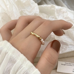 Primer plano detallado de un anillo ondulado dorado con tres delicadas perlas pequeñas