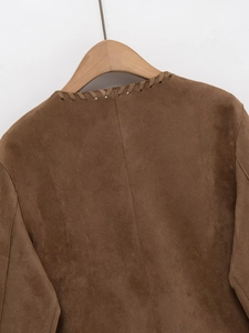 Détails des coutures du col d'une veste en daim marron sur un cintre en bois