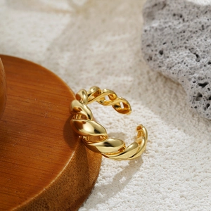 Macro shot of 18K gold-plated twisted ring on a rustic wooden tray with natural textures