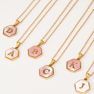 Detail of gold hexagon necklaces with pink shell inlay and 3D metallic letters
