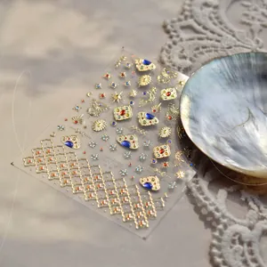 Exotische goldene Nagelaufkleber mit Edelsteinmustern auf weißer Spitze