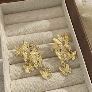 Close-up of golden butterfly earrings with detailed textures in a soft velvet box