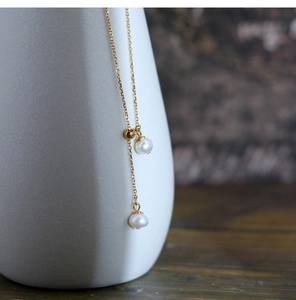 Detail of adjustable gold-plated chain with natural freshwater pearl tassels on a ceramic vase