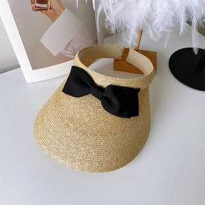 Straw sun visor with large black bow on elegant white display with feather accents