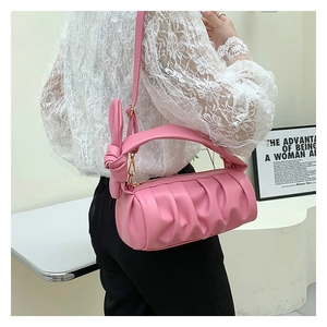 Close-up of pink pleated cloud bag featuring decorative knots and chain strap detail