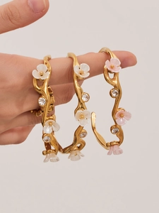 Detail view of gold floral cuff bracelets with resin petals and sparkling rhinestones