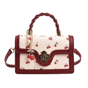 Chic cream handbag with red cherry print, woven handle and gold flower lock detail